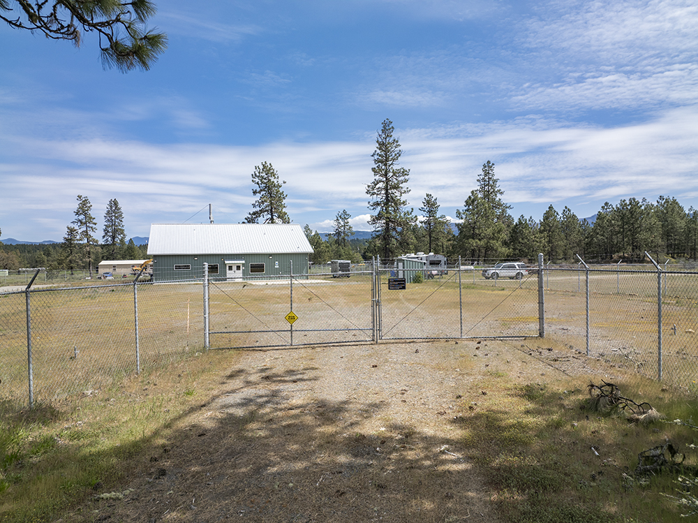 Secure perimeter fencing with gated entry surrounding 1.38-acre industrial lot at 30073 Redwood Hwy in Cave Junction, OR.