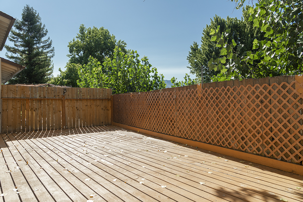 Private fenced backyard with spacious wooden deck and side yard access.
