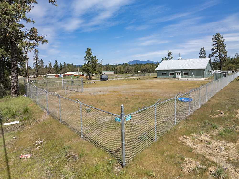 Secure perimeter fencing with gated entry surrounding 1.38-acre industrial lot at 30073 Redwood Hwy in Cave Junction, OR.