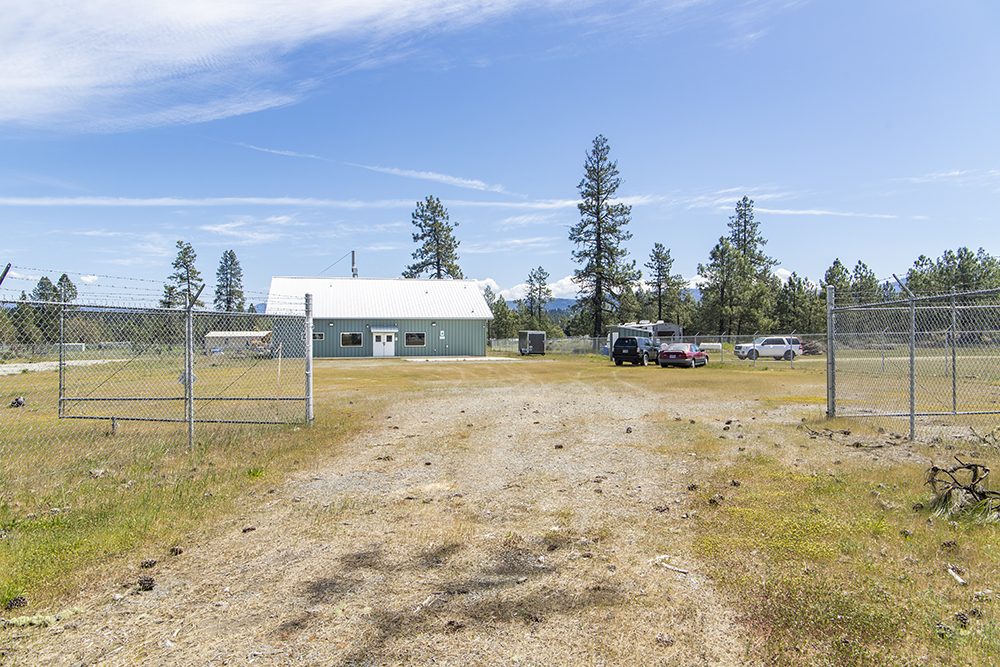 Secure perimeter fencing with gated entry surrounding 1.38-acre industrial lot at 30073 Redwood Hwy in Cave Junction, OR.