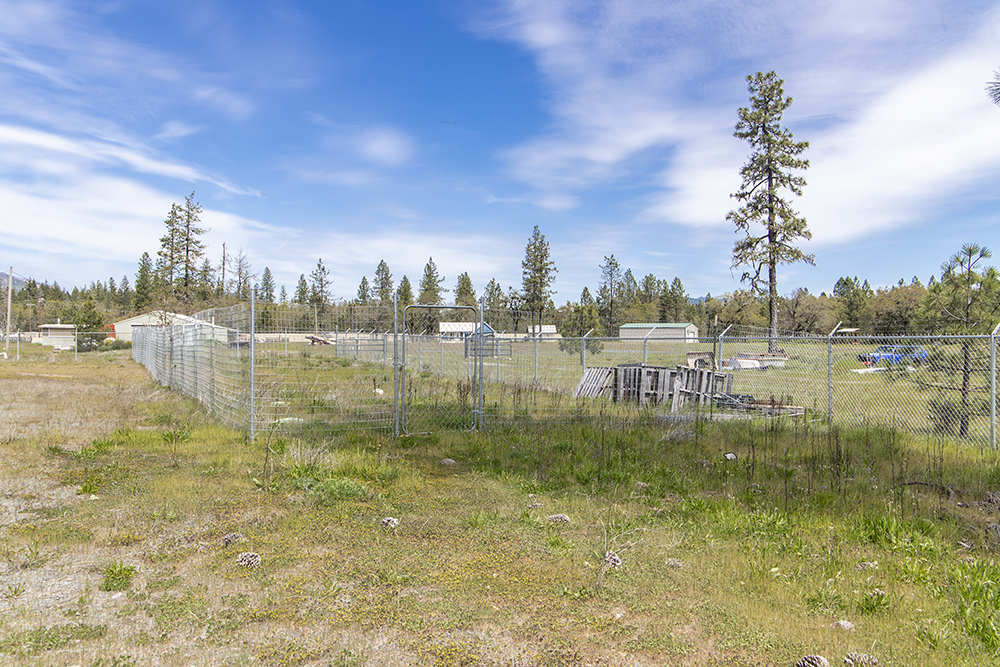 Secure perimeter fencing with gated entry surrounding 1.38-acre industrial lot at 30073 Redwood Hwy in Cave Junction, OR.