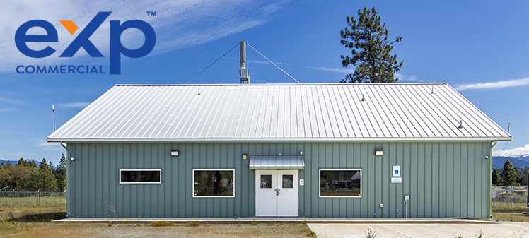 Exterior view of 30073 Redwood Highway – modern commercial building with metal roof, secured fencing, gated entry, and paved parking area, located in Cave Junction, Oregon.