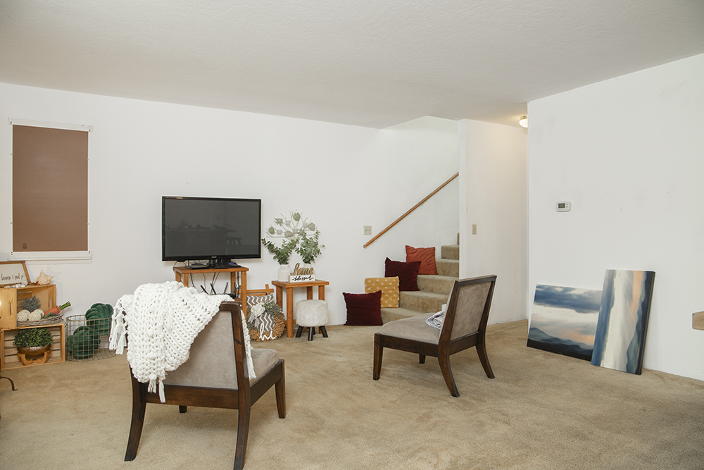 Bright living room with carpet flooring, large front-facing window, and open layout.