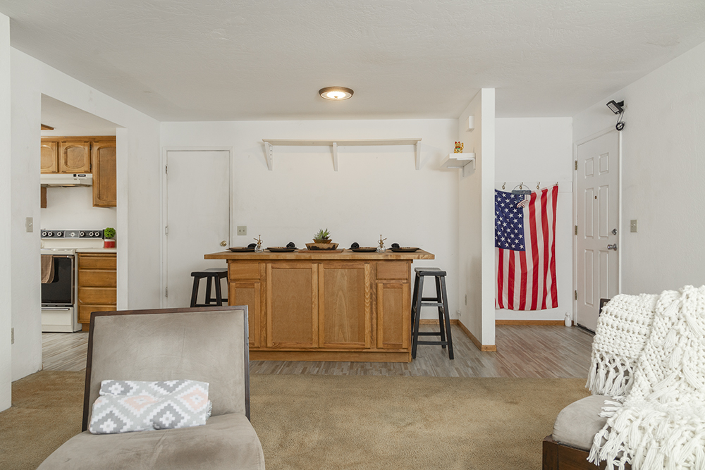Bright living room with carpet flooring, large front-facing window, and open layout.