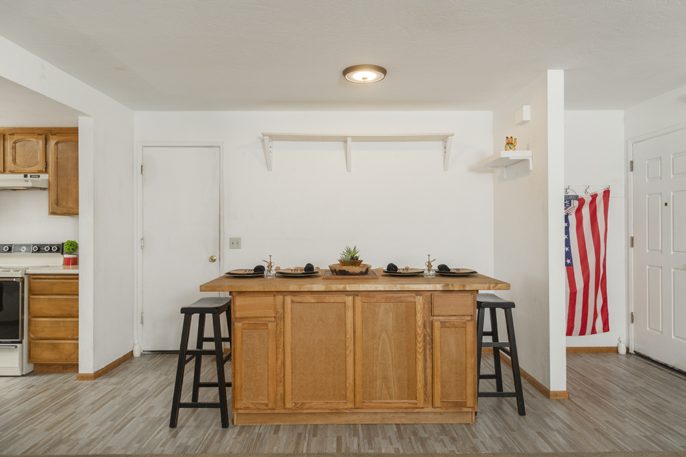 Bright living room with carpet flooring, large front-facing window, and open layout.