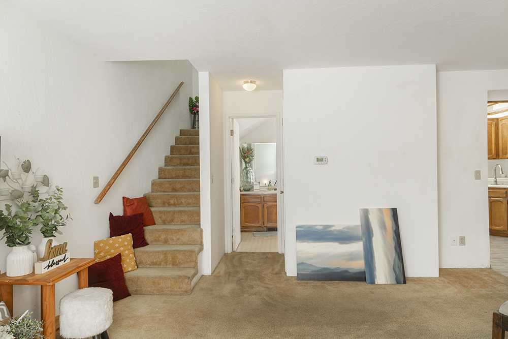 Bright living room with carpet flooring, large front-facing window, and open layout.